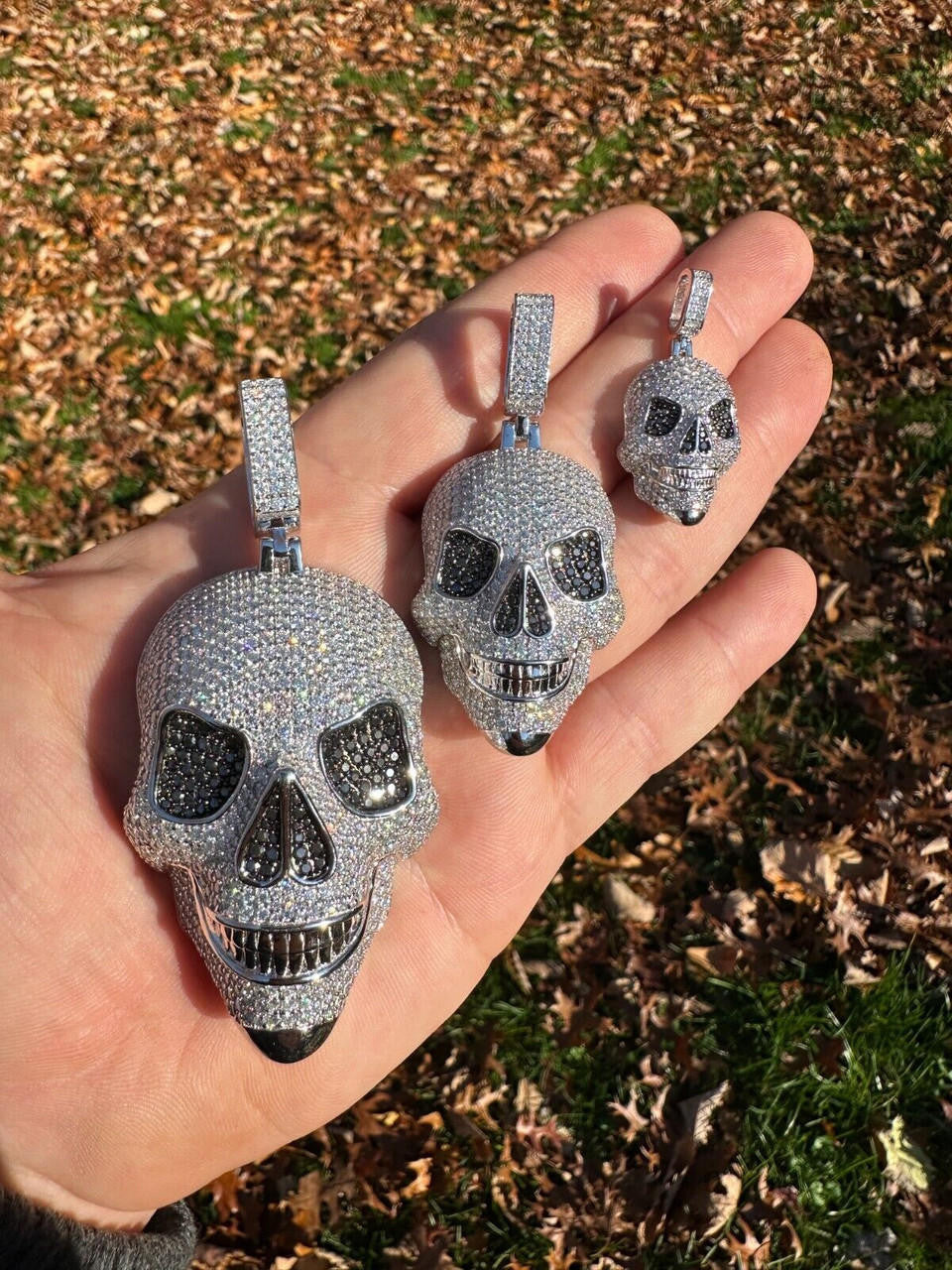 A men Holding three Different Sizes of 14k White Gold Skull Pendants