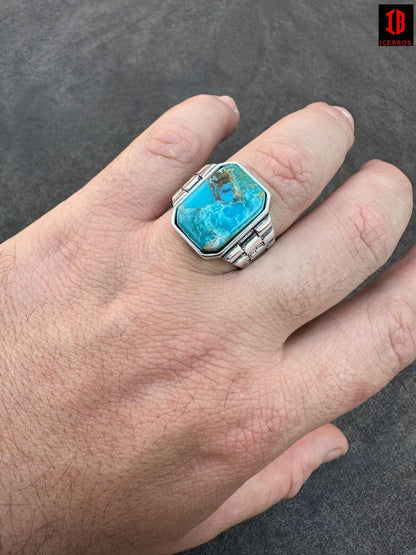 The image depicts a man's hand showcasing a ring featuring a stunning turquoise stone.