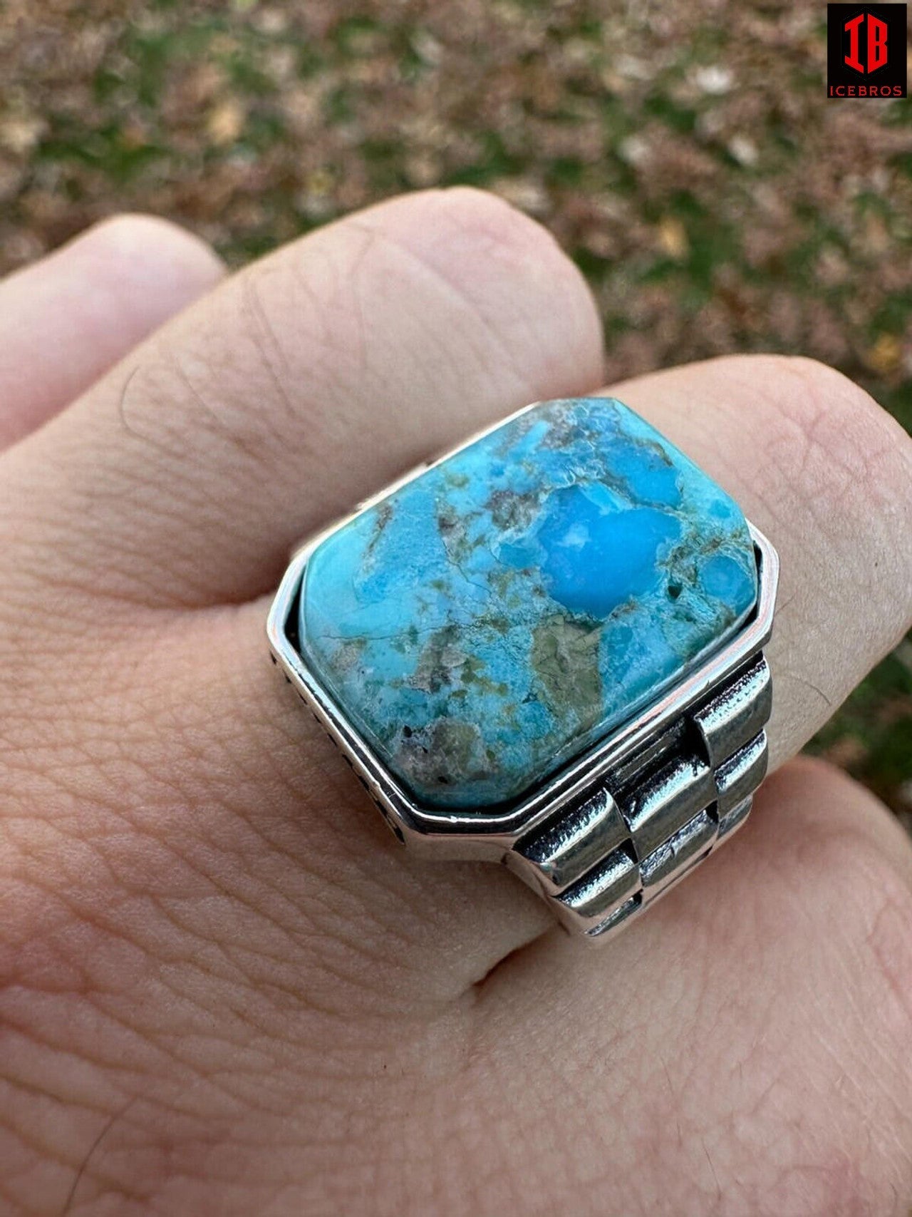 A person's hand showcasing a sterling  silver ring adorned with a beautiful blue turquoise stone.