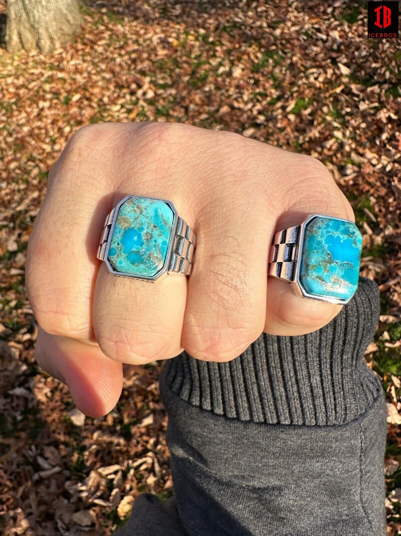 A man's hand showcasing two rings adorned with turquoise stones, exuding elegance and style.