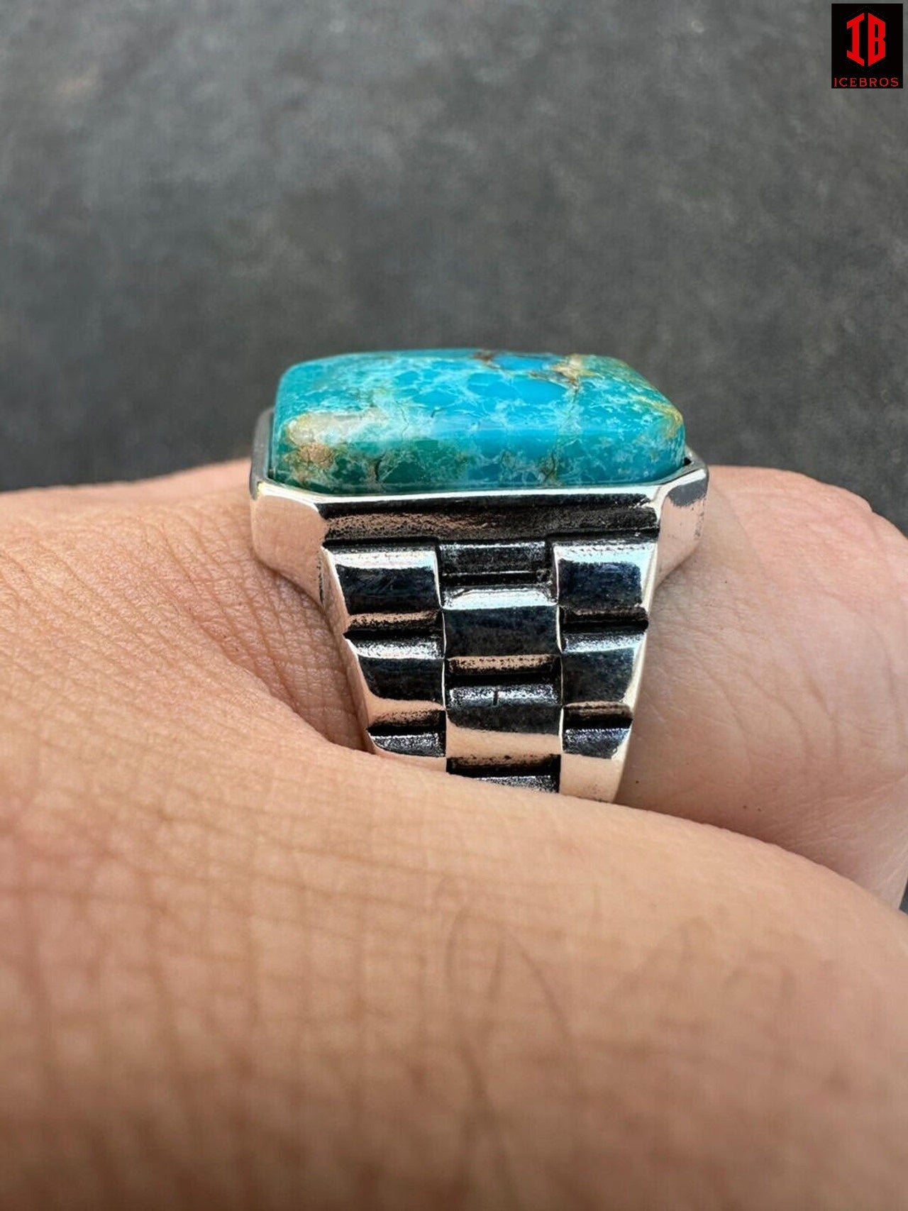 A man's hand showcasing a ring with a turquoise stone, radiating elegance and charm.