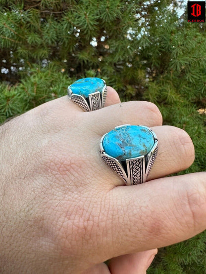 A man's hand showcasing two rings adorned with blue turquoise stones, exuding elegance and style.