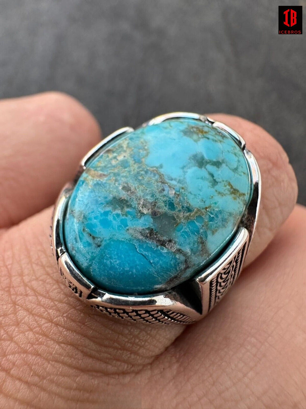 A hand wearing a turquoise stone ring, showcasing its vibrant color and the elegance of the jewelry piece.