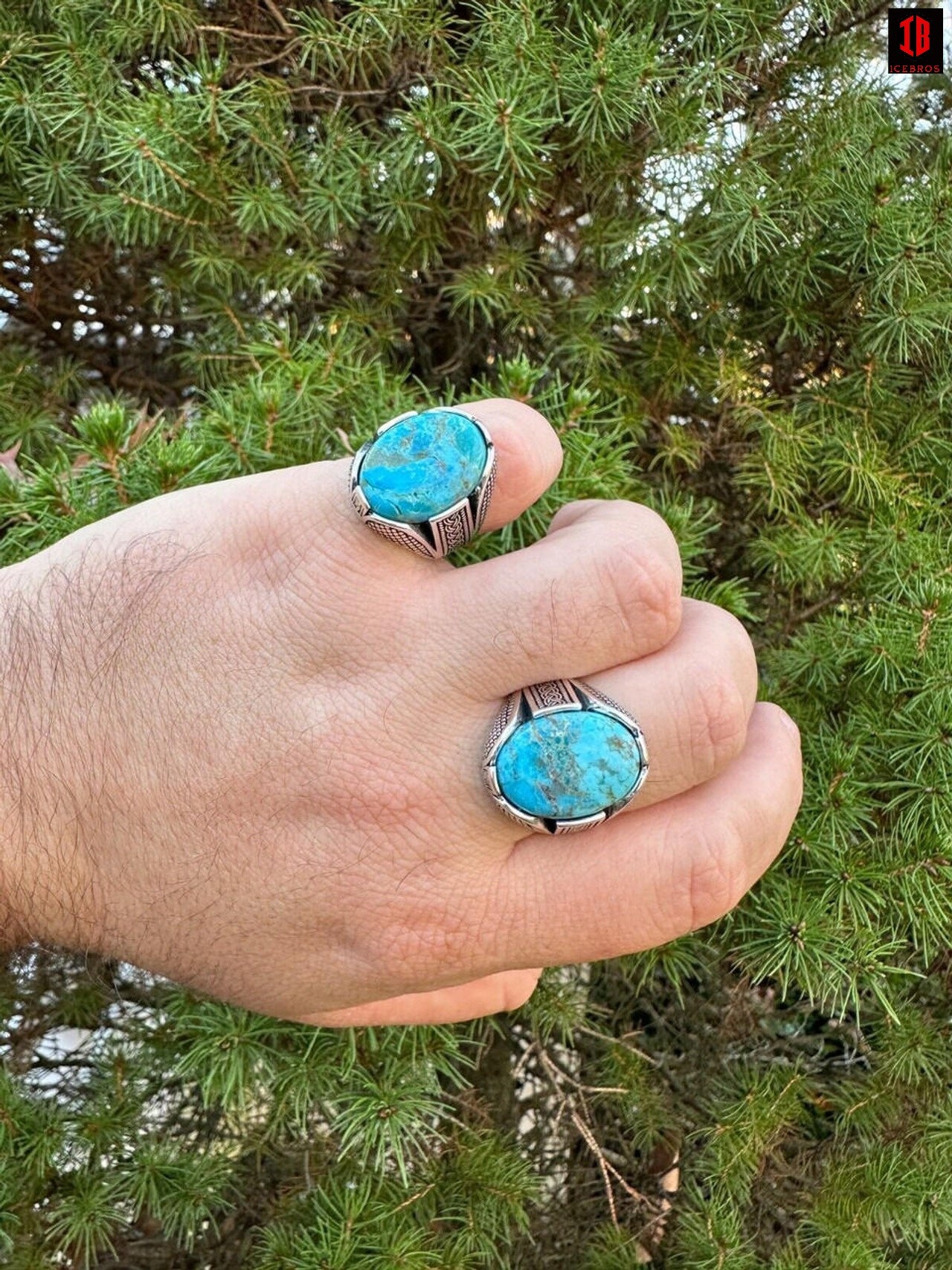 A hand holding two turquoise rings, showcasing their vibrant color and elegant design.