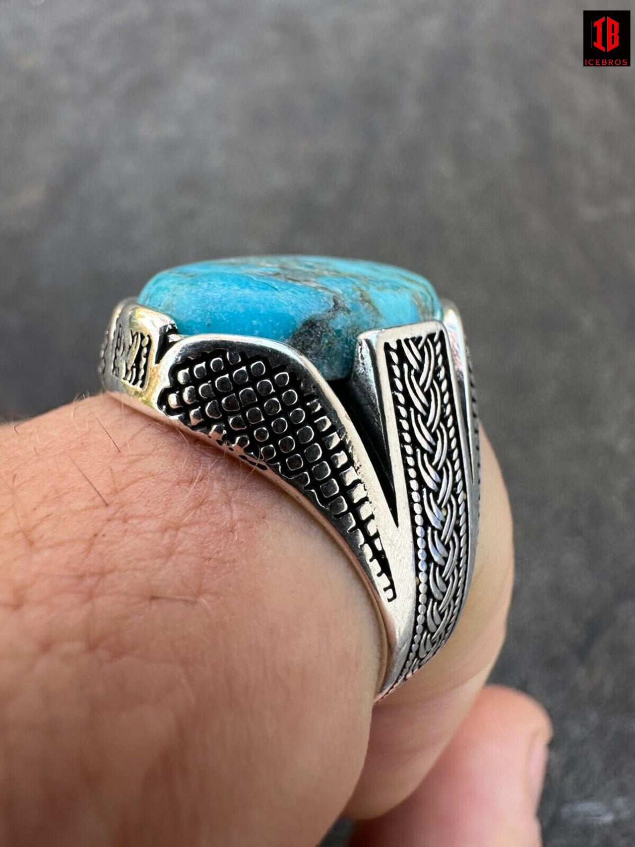 A man's hand showcasing two rings adorned with blue turquoise stones, exuding elegance and style.
